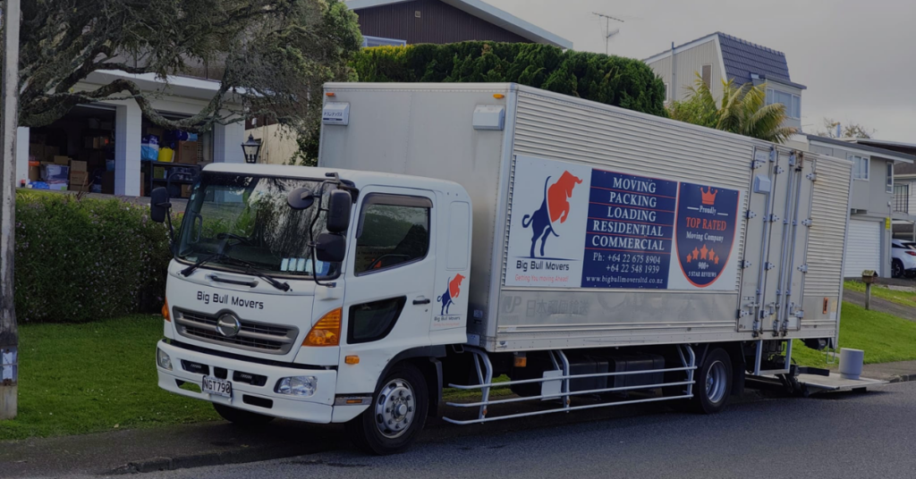 Furniture movers in North Shore carrying a sofa from a house into a moving truck